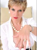 Mature business lady poses by her table with her large heavy jugs almost bare