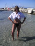Shameless older babe soaks her white tee up to flash her big jugs at the beach