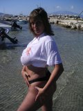 Shameless older babe soaks her white tee up to flash her big jugs at the beach