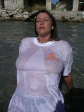 Shameless older babe soaks her white tee up to flash her big jugs at the beach